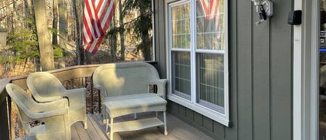 A wooden deck with wicker furniture and an American flag.