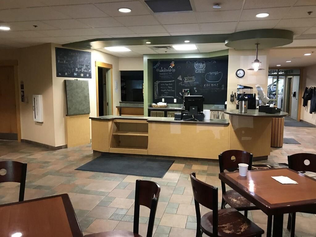 A cafe with a counter, seating area, and a chalkboard menu.