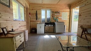 A compact kitchen with wooden walls, a small countertop, and a glass table. - “The Summit Cabin” <br>An Off the Grid Hideaway (Barnardsville)
