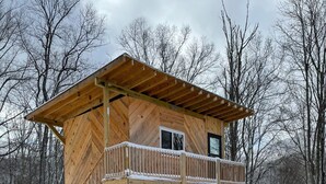 A wooden cabin with a balcony, a covered porch, and a staircase leading to the upper level. - “The Summit Cabin” <br>An Off the Grid Hideaway (Barnardsville)