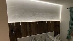 Ein Schlafzimmer mit einem hölzernen Kopfteil, einem Nachttisch und einem grünen Vorhang.