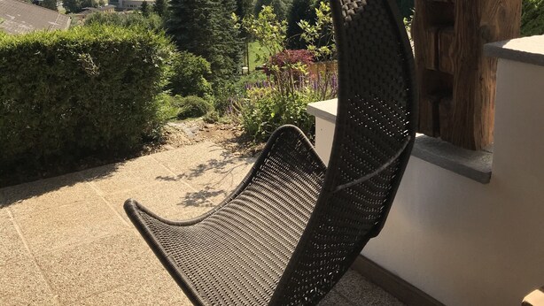 Ein Hängestuhl mit Blick auf eine malerische Seenlandschaft, Berge und ein Dorf.