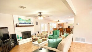 A spacious living room with a fireplace, a television, and a dining area with wooden furniture. - Private Oasis Near Old Mesilla - Home with Pool/Spa (Las Cruces)