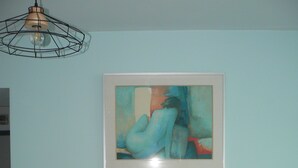 A room with a bookshelf containing books and a framed abstract painting on the wall. - Maison D'hôtes Chambre Champêtre (La Chailleuse)