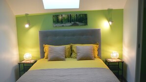A bedroom with a bed, two bedside tables, and a painting on the wall. - Maison D'hôtes Chambre Champêtre (La Chailleuse)