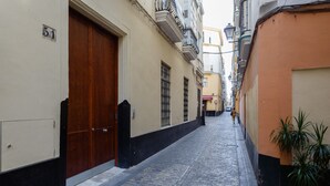 A narrow cobblestone street flanked by buildings with large wooden doors and barred windows. - CRUISE Adapted Apartment by Cadiz4Rentals (Cádiz)