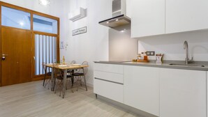 A modern kitchen with white cabinets, a stainless steel sink, and a dining area with a table and chairs. - CRUISE Adapted Apartment by Cadiz4Rentals (Cádiz)