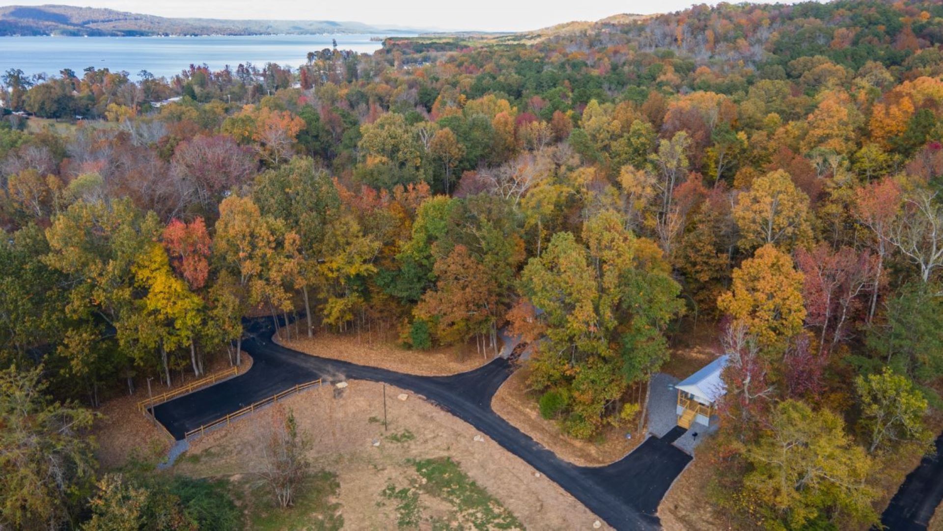 An aerial view of a forested area with a winding road and a small building.