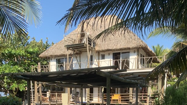 Un área de piscina con sillones de descanso y una estructura con techo de paja.