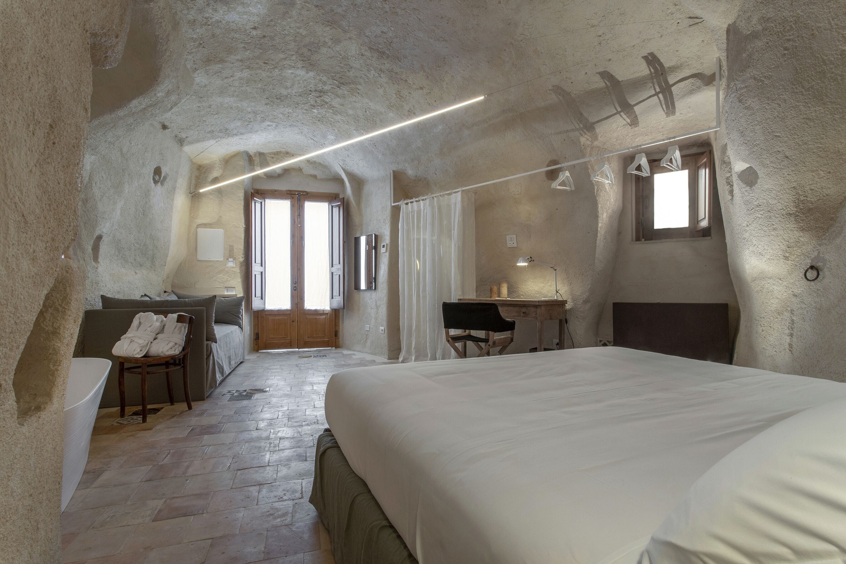 Ein Schlafzimmer mit einem großen Bett, einem Schreibtisch, einem Stuhl und einem Badezimmer.