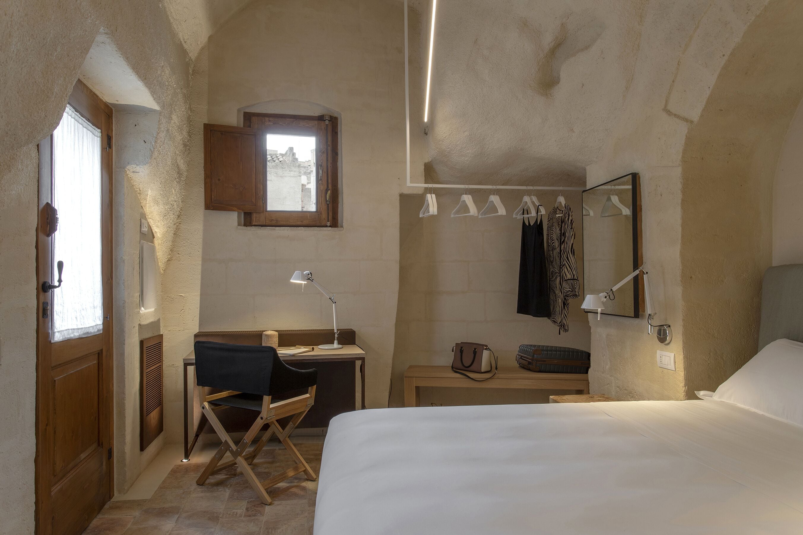 A bedroom with a bed, desk, chair, and a window.