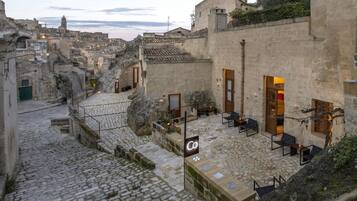 Un patio con suelo de piedra, mobiliario exterior y una pared de piedra con una puerta.