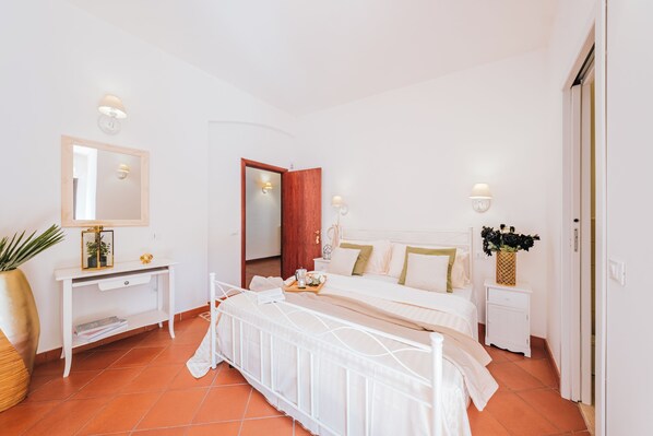A bedroom with a bed, bedside tables, a mirror, and a door.