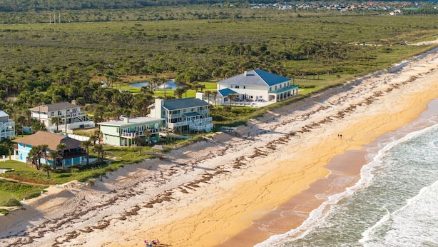 A beachfront property with multiple houses, a sandy beach, and a view of the ocean. - Tipsy Turtle Direct Oceanfront Sunrise (Palm Coast)