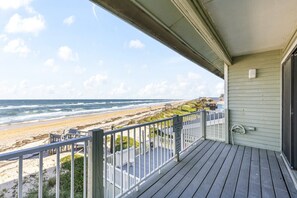 A wooden deck with a view of the beach and ocean.