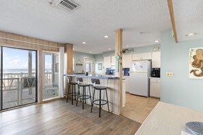 A kitchen with a bar area, a refrigerator, and a view of the ocean.