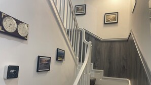 A staircase with a wooden finish, white railings, and a wall-mounted clock. - 5 bed, 5 bath, Slps 18, Town Ho. 60 yds Weymth beach & harbour, NEWLY RENOVATED! (Weymouth)