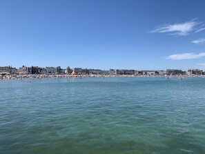 Un paysage urbain côtier avec une vaste plage et un ciel bleu dégagé.