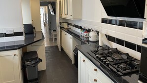 A modern kitchen with white cabinets, black countertops, and a gas stove. - 5 bed, 5 bath, Slps 18, Town Ho. 60 yds Weymth beach & harbour, NEWLY RENOVATED! (Weymouth)