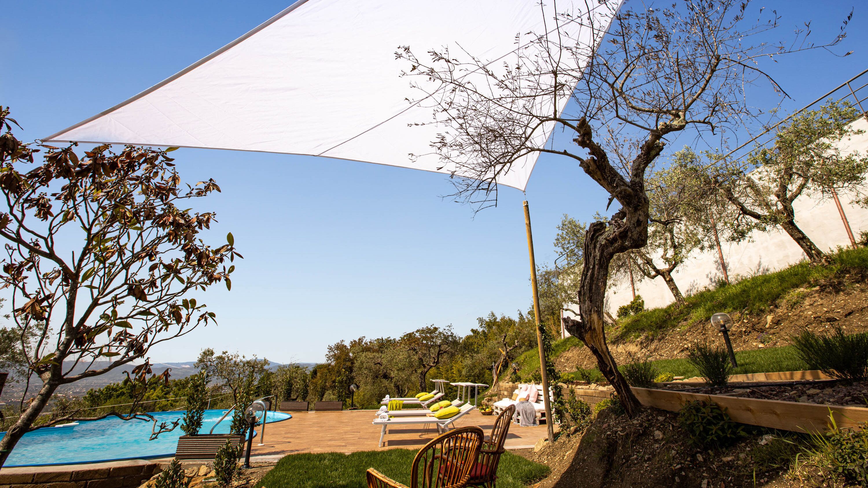 A pool area with lounge chairs, a table, and a large white canopy.