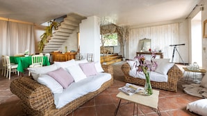 Un vaste espace de vie doté d’un haut plafond, d’un escalier et d’un coin repas avec une nappe verte.