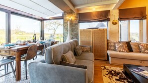 Ein modernes Wohnzimmer mit Essbereich, großen Fenstern und einer Steinwand.