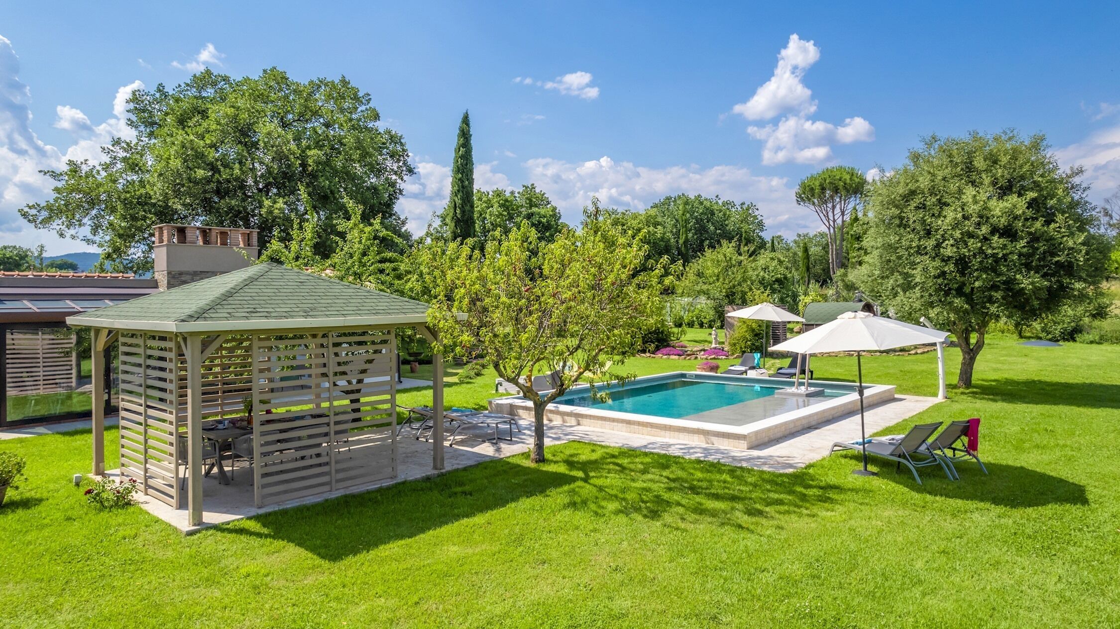 Un giardino sul retro con piscina, gazebo e zona patio coperta.
