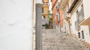 A narrow street with stone steps leading up to a row of buildings with balconies.