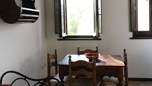 Ein Essbereich mit Holztisch und Stühlen, einem Fenster mit geöffneten Lamellen und einem Deckenventilator.
