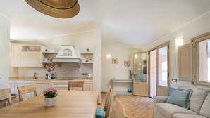 Une cuisine moderne avec des meubles blancs, une table à manger en bois et un four encastré.