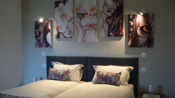 A bedroom with a large bed, two pillows, and a nightstand with a lamp. - Maison D'hôtes Chambre Family (La Chailleuse)