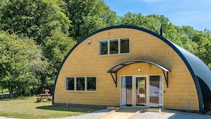 A single-story, curved brick building with a flat roof, large windows, and a door with glass panels. - Ledge View  - sleeps 6 guests  in 3 bedrooms (Weston Subedge)