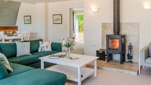 A cozy living room with a green sofa, a white coffee table, and a wood-burning stove. - Ledge View  - sleeps 6 guests  in 3 bedrooms (Weston Subedge)