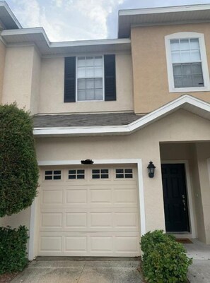 Two-story residence with a modern architectural style, featuring a flat roof and a small overhang above the garage.