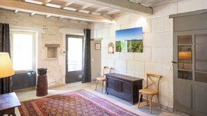 Una stanza con parete in pietra, camino, tappeto decorato e panchetta in legno.