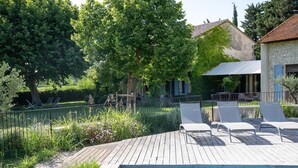 Un pontile in legno con piscina, lettini e un edificio in pietra con tetto in tegole.