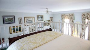 Un dormitorio con cama, ventilador de techo y balcón con barandilla.