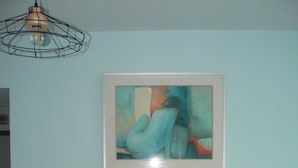 Una habitación con una estantería llena de libros y un cuadro abstracto enmarcado en la pared.