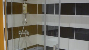 Ducha envuelta en vidrio con cabezal de ducha de mano y grifo empotrado.