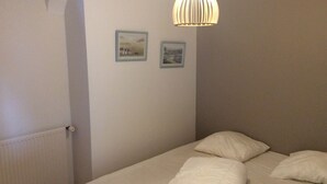 Una camera da letto con un letto, un termosifone e due quadri appesi al muro.