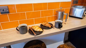 Eine Küchenarbeitsplatte mit einem Toaster, einer Kaffeemaschine und Croissants auf Tellern.