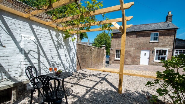 Eine Terrasse mit Pergola, einem Tisch und Stühlen sowie einem Kiesweg.