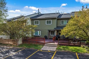 A two-story residential building with a front porch, a driveway, and a parking area. - Close to the Slopes! On Free Bus Route! Summer Pool! (Steamboat Springs)