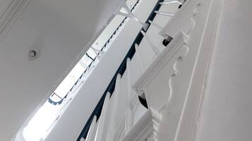 A spiral staircase with white walls and a circular skylight.
