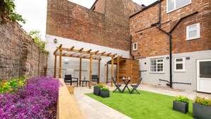 A courtyard with a wooden pergola, seating area, and planters with flowers. - Bricksage Rooms, King's Lynn South Gate (King's Lynn)