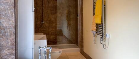 Une salle de bain moderne avec une douche en verre, un lavabo blanc et un porte-serviettes avec une serviette jaune.