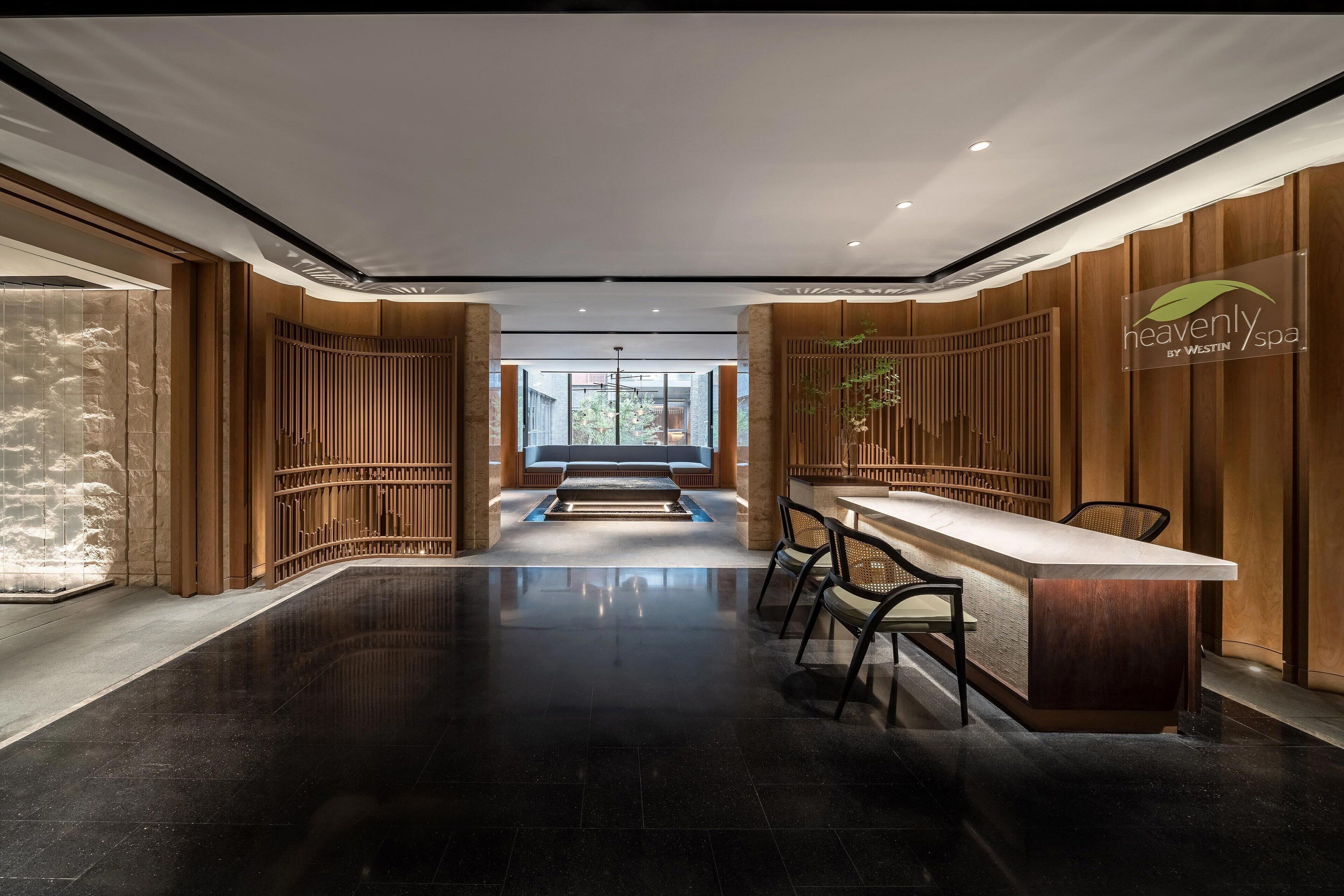 A modern spa interior with a reception desk, seating area, and a view of the outdoors.