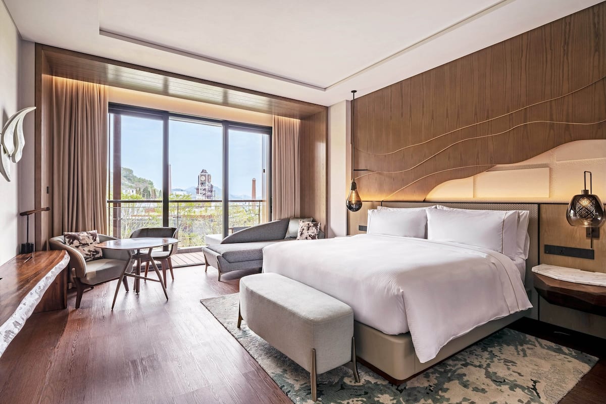 Een moderne hotelkamer met een groot bed, een bureau, een stoel en uitzicht op de stad.