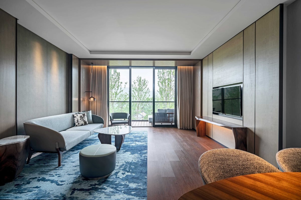 Een moderne hotelkamer met een bank, twee fauteuils, een salontafel en een televisie.