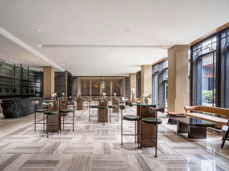 Un vestíbulo amplio con muebles modernos, ventanas grandes y una zona de estar central.